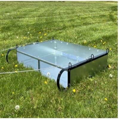 Reflective glass box on grassy field with flowers